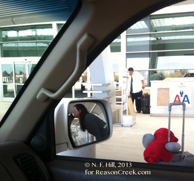 Young woman gives a kiss to her childhood puppy as she departs to airport after a visit with her parents.