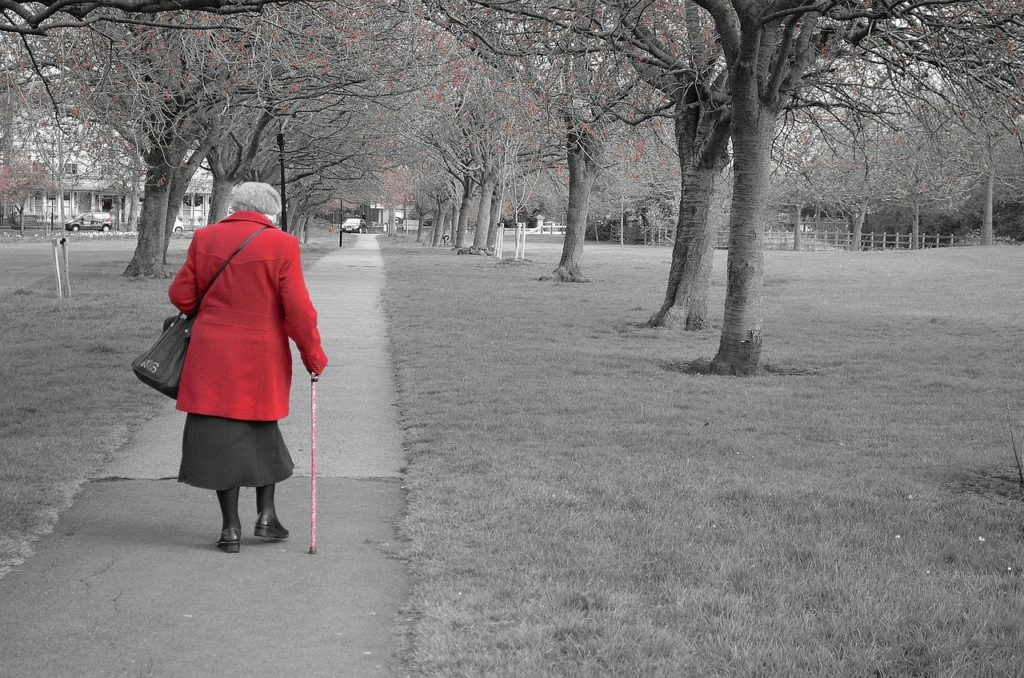 old woman walking in an urban park 