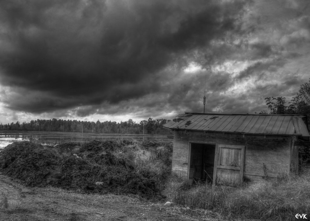 Stormy weather coming in over an old decrepit shed. black and white image.