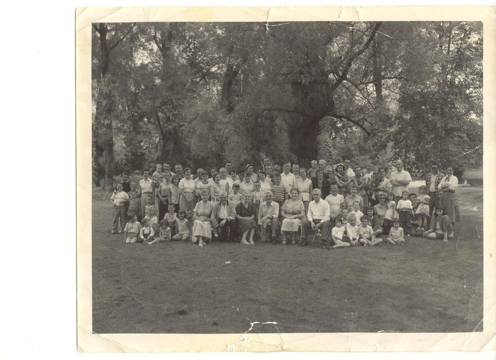 Extended family gathering black and white portrait snapshot. Posed outside on grassy area in front of grove of trees. Probaby early mid 20th century. 