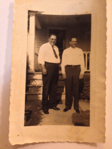 Two men in white button-front shirts and dress slacks. They are identified as brothers Lester and Fred standing in front of a house in Fort Wayne Ind. in July of 1939. 